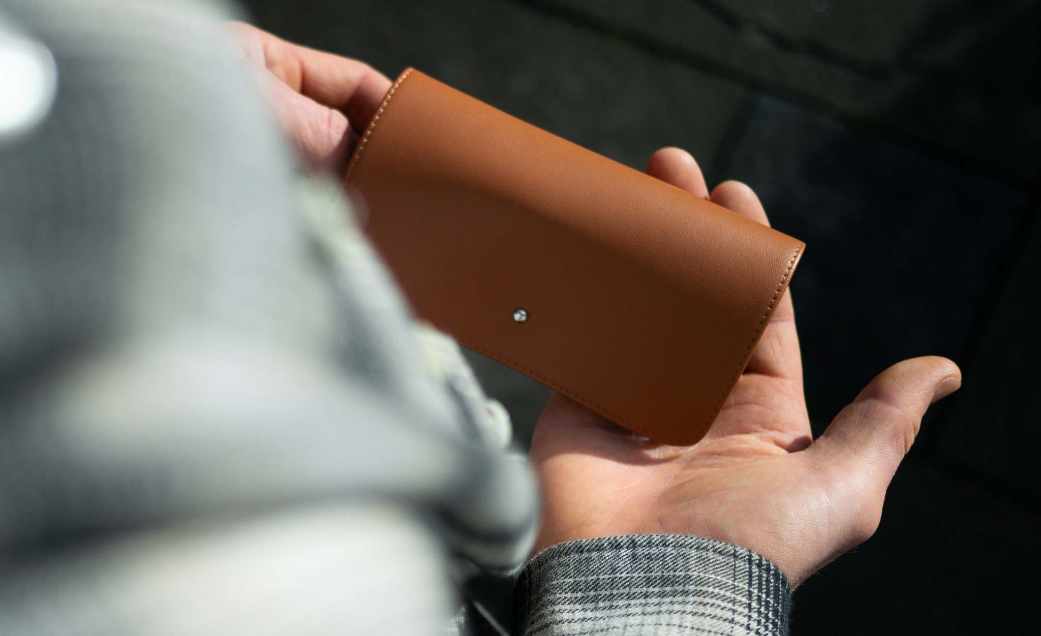Person holding tan leather spectacle case