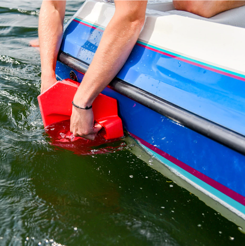 Person placing wake shaper on side of boat. 