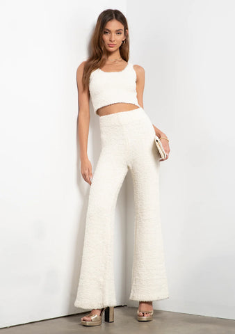 Woman in long flared white pants with a white strappy crop top