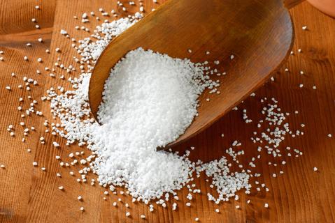 epsom salt on a wooden surface coming out of a wooden scoop