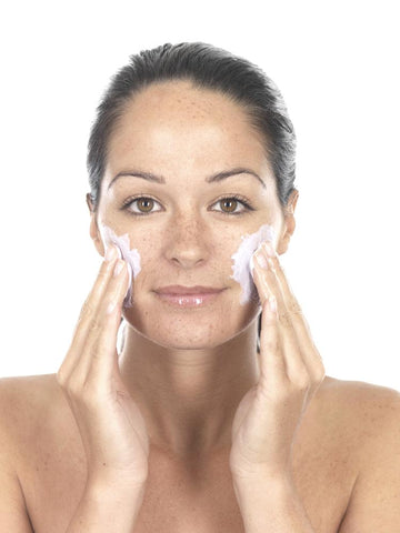 young woman exfoliating before an at-home facial