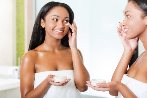 woman looking in the mirror while applying eye cream