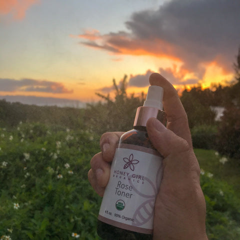 Honey Girl Organics Rose Toner spritz in front of the sunset