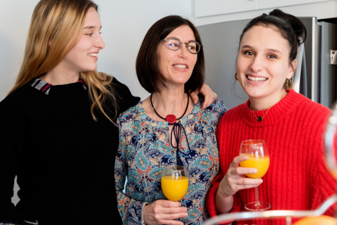 Two younger ladies surround an older woman holding mimosas.