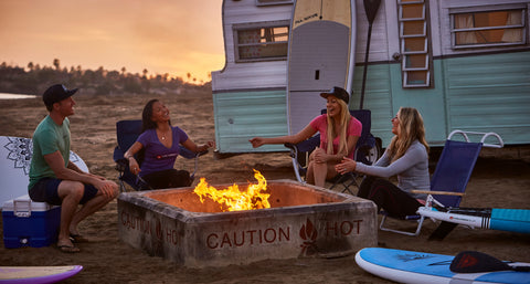 Stand Up Paddle Boarders enjoying a break on around a camp fire