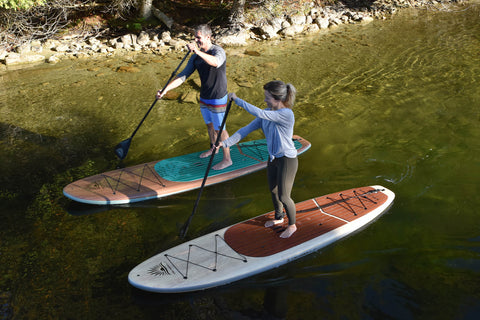 two stand up paddle boarders on a lake