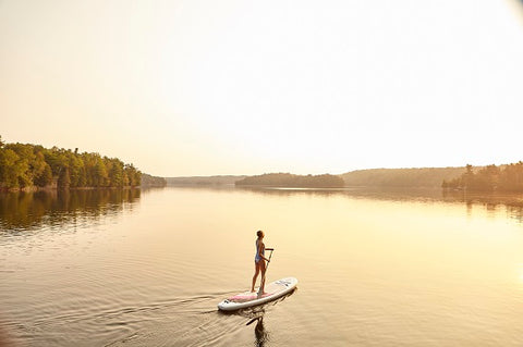 A stand up paddle boarder in very calm water