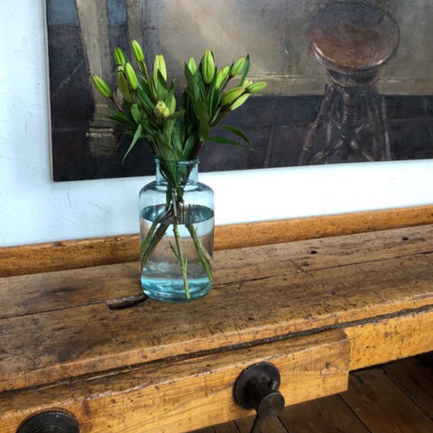 Tuscan Style Home Décor: A Guide The 5 Main Things to Know - An antique Tuscan woodworkers bench which is used for serving when entertaining, and a vintage market jar used as a vase, both from MERCATO Antiques. The student artwork was purchased from The New York Academy of Art.