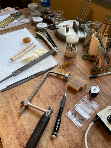 A jeweler's bench with a saw, a file, and wax carving tools.