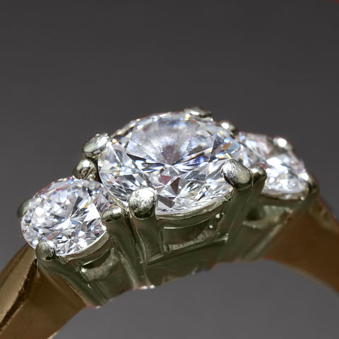 A three-diamond ring set in yellow gold, with worn-out prongs.