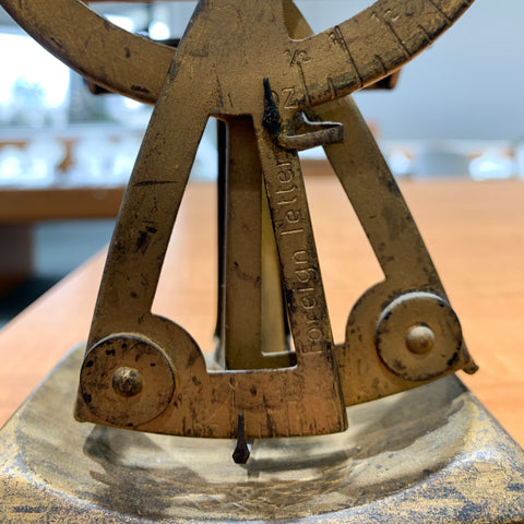 A closeup of the bottom of an antique postal scale, showing the markings for Foreign Letters.