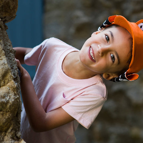 child wearing orange classic baseball cap with a child-friendly roll-up neck protector as featured on little hotdog watson blog