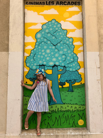 Child in doorway in front of street art in Anduze