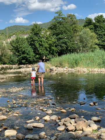 Father and daughter walking in the river in Anduze
