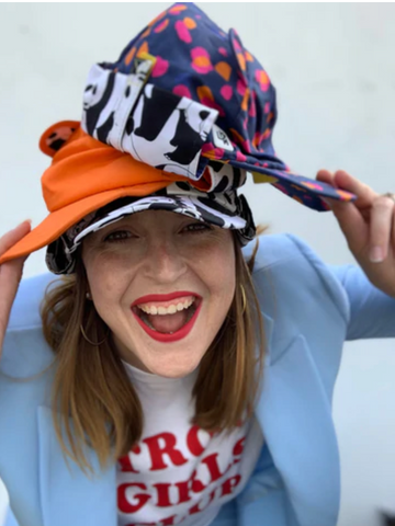 Woman Wearing three hats and blue suit founder of Little Hotdog Watson, Emma Watson