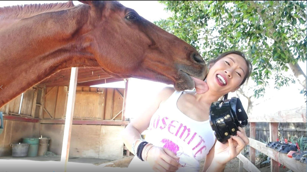 A woman being licked by her brown horse whilst reviewing Scoot Boots
