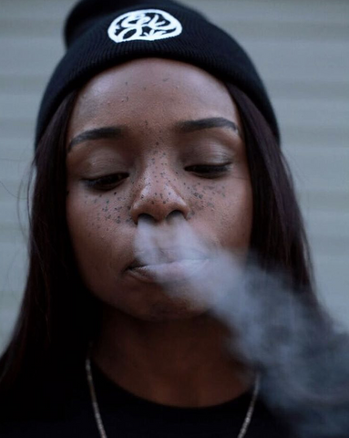 Woman wearing beanie, blowing smoke