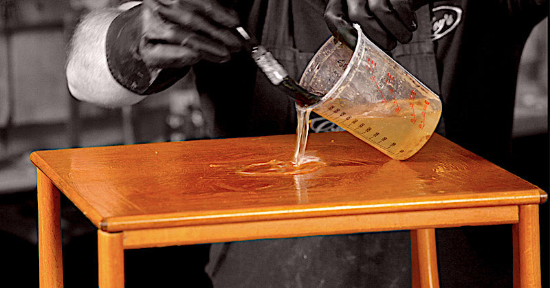 pouring the stripper on the surface of the Nathan teak table