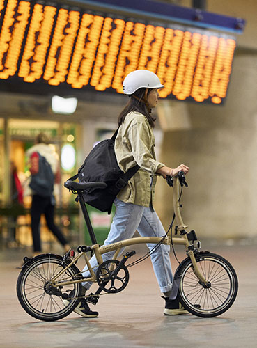 Frau schiebt Brompton-Fahrrad durch Flughafen