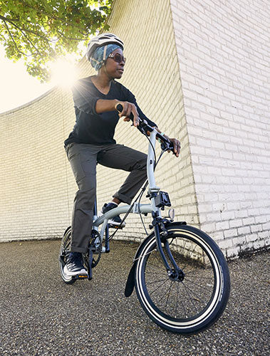 Frau fährt auf Brompton Fahrrad um die Ecke