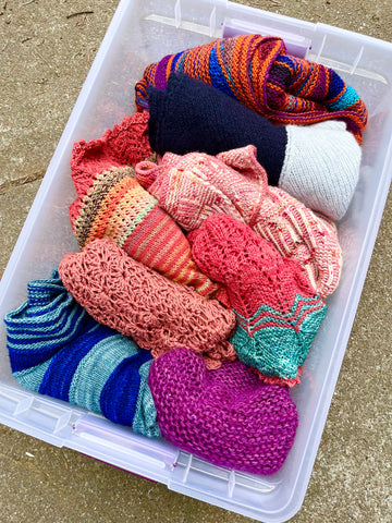Plastic tub with hand knit shawls. 