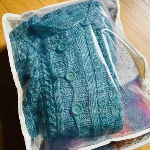 Hand knit sweaters in a sweater bag.