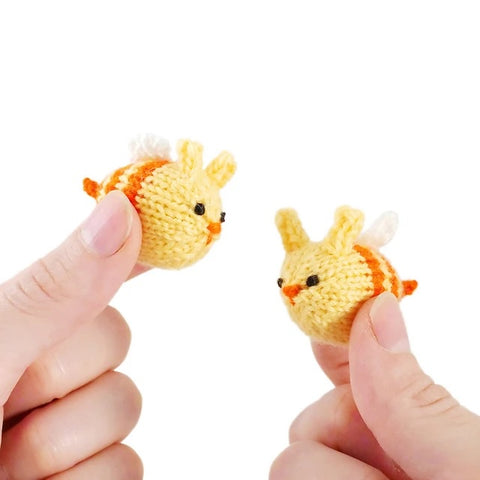 Two hands each holding a tiny Bunnybee toy.