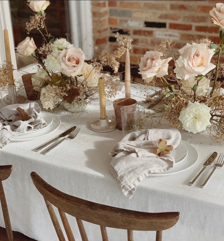 Lovely wedding table dressed in a white linen tablecloth and large pale pink roses.