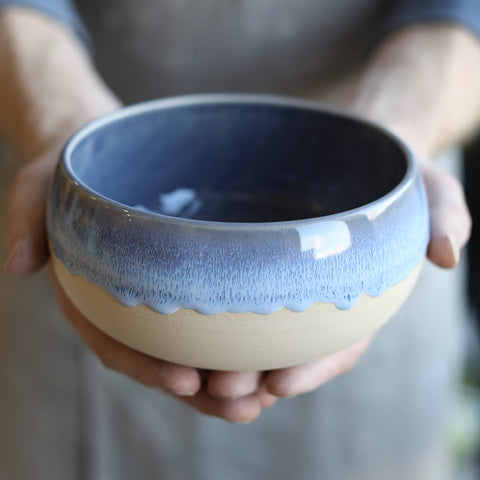  A finished Glosters Acorn Soup Bowl in Midnight Blue sits in a potters hands.