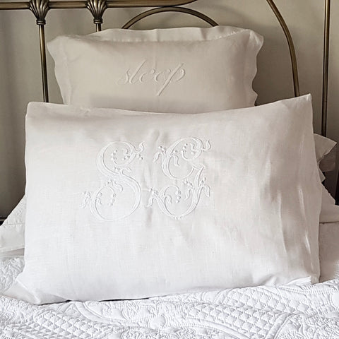 White bed pillows featuring a large French monogram in the centre.