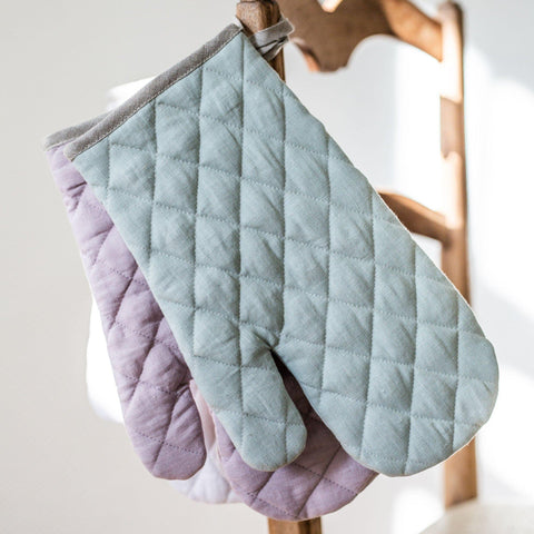 Three Linen and Letters Quilted Oven Mitt hanging on a wooden chair: Sage Green, Dusky Lavender, Dusky Rose Pink