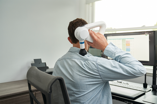 Using Theragun Elite massage device at the desk in the office