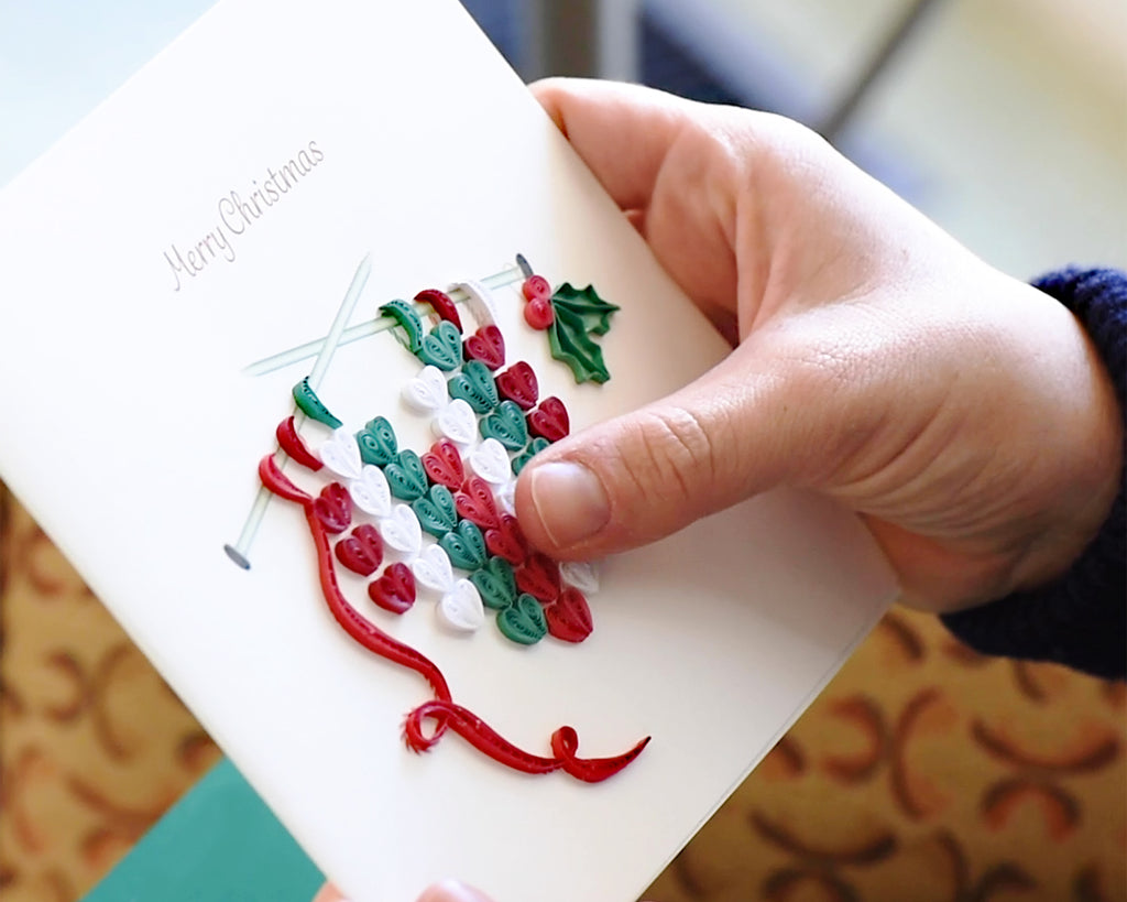 A hand holding a Quilled Knit Heart Christmas Card.