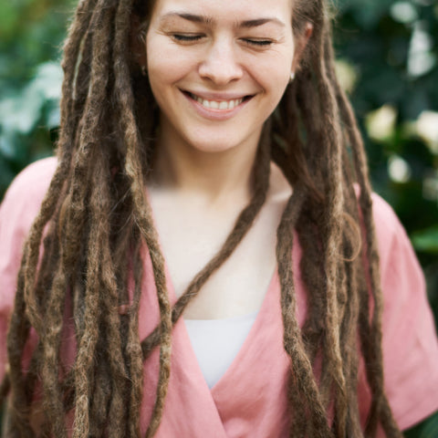 Woman with dreadlocks looking down and smiling