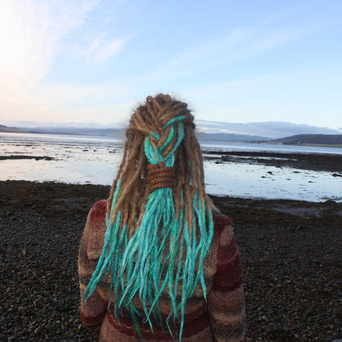 girl with dreadlocks looking away towards the sea