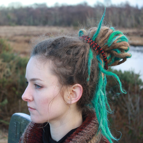 Girl with dreadlocks looking to the left with spiral hair tie in hair