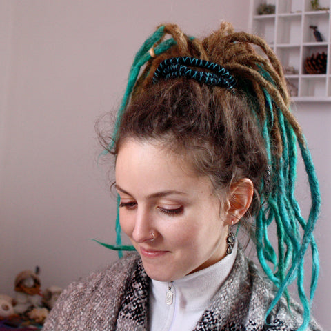 girl with dreadlocks looking down with her hair tied up with a bendable spiral hair tie