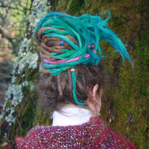 girl with dreadlocks looking away with a hair tie in her hair