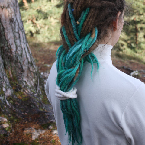 girl looking away with dreadlocks with her hair braided and tied together with a spiral hair tie