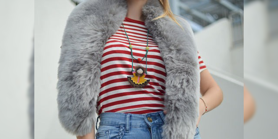 a woman wearing a red and white striped shirt, blue jeans, a grey fur vest and a