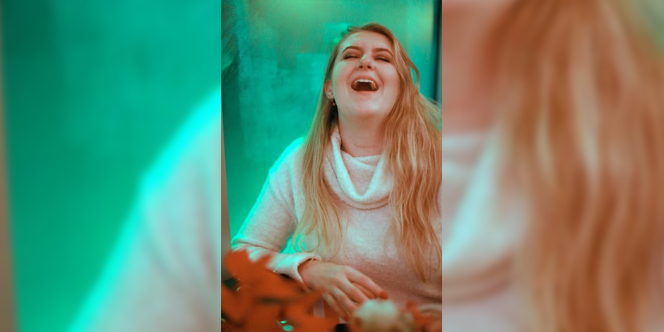 girl laughing, wearing a white sweater