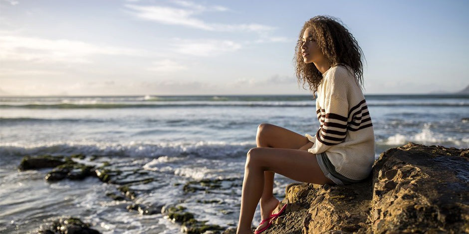 girl wearing solid white and solid black sweater sitting at the beach