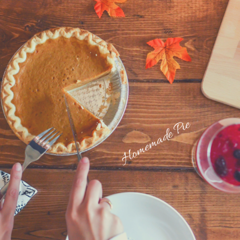 person slicing a piece of pumpkin pie on a wooden table