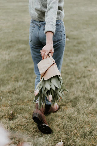 someone holding a bunch of flowers in a field with a person walking by