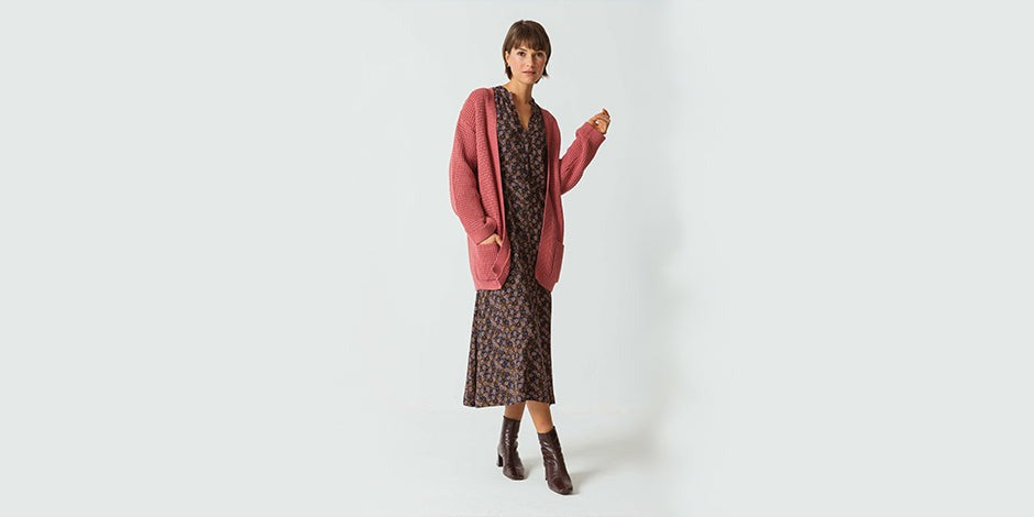 there is a woman standing in a dress and cardigan
