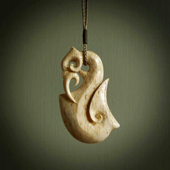 A deer antler bone hook pendant with a manaia head