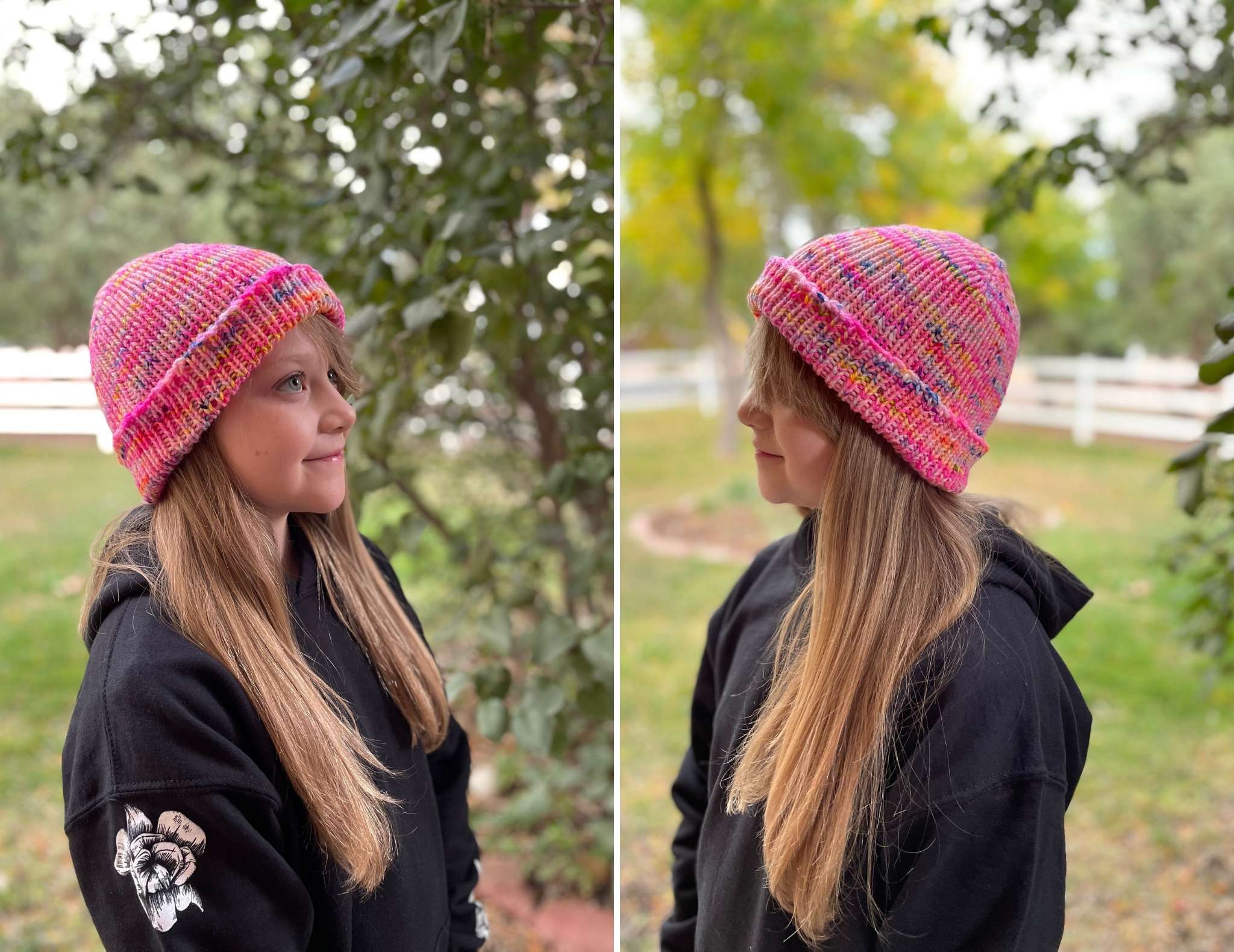a young teenager with long brown hair is photographed in a park wearing a black hoodie and a bright pink hat. The hat has variegated shades of pink, yellow and dark grey and is worn with the brim turned up.