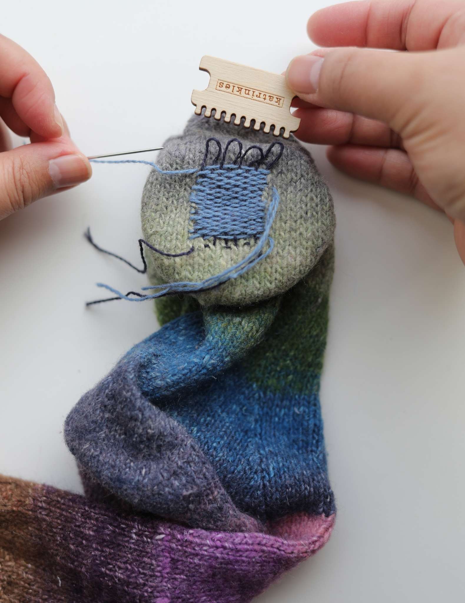 The heddle has been removed from the sock, leaving the patched hole with the loops that were around the heddle teeth loose at the top.