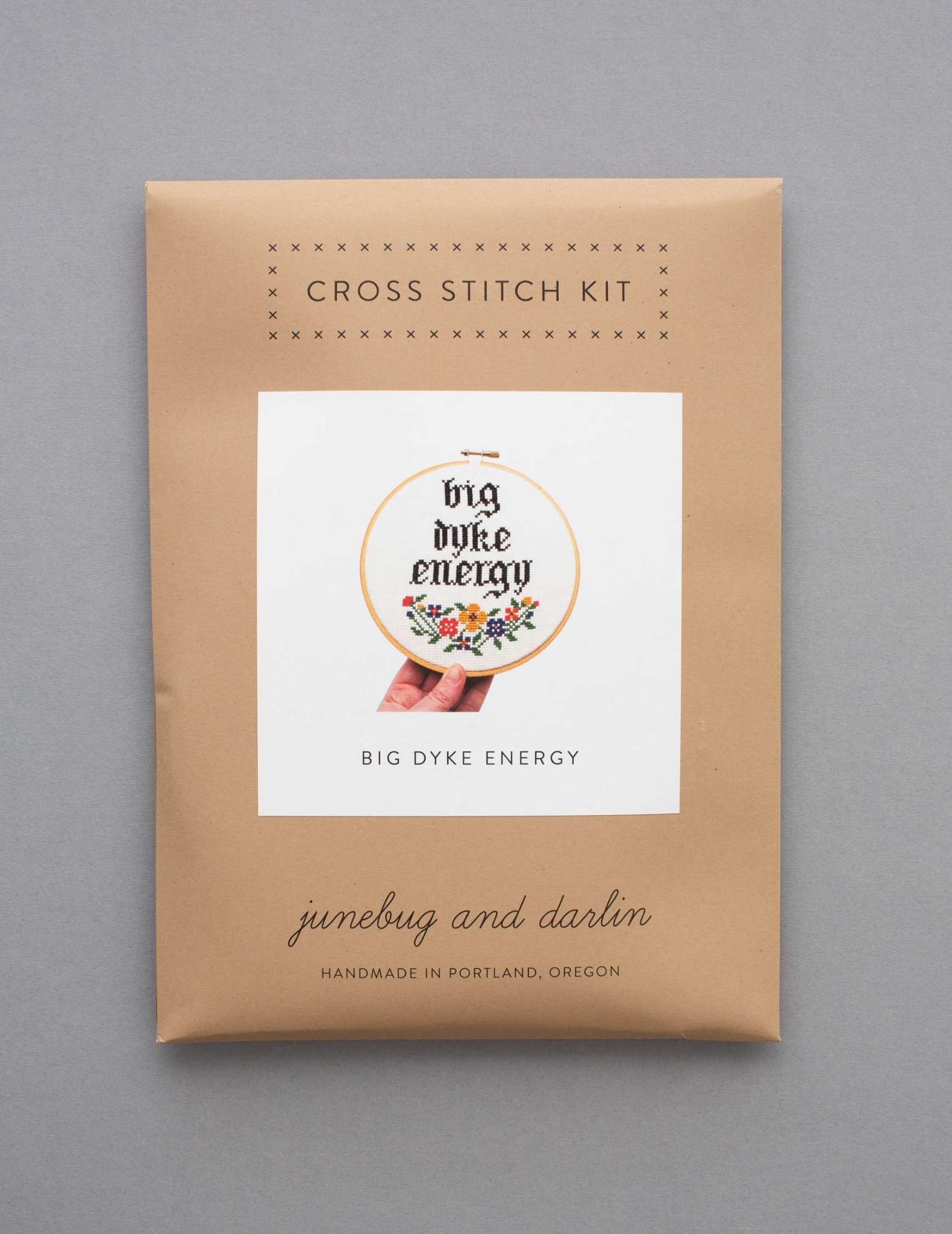 A cross stitch kit in a brown enveloping showing a design with the text 'Big Dyke Energy'