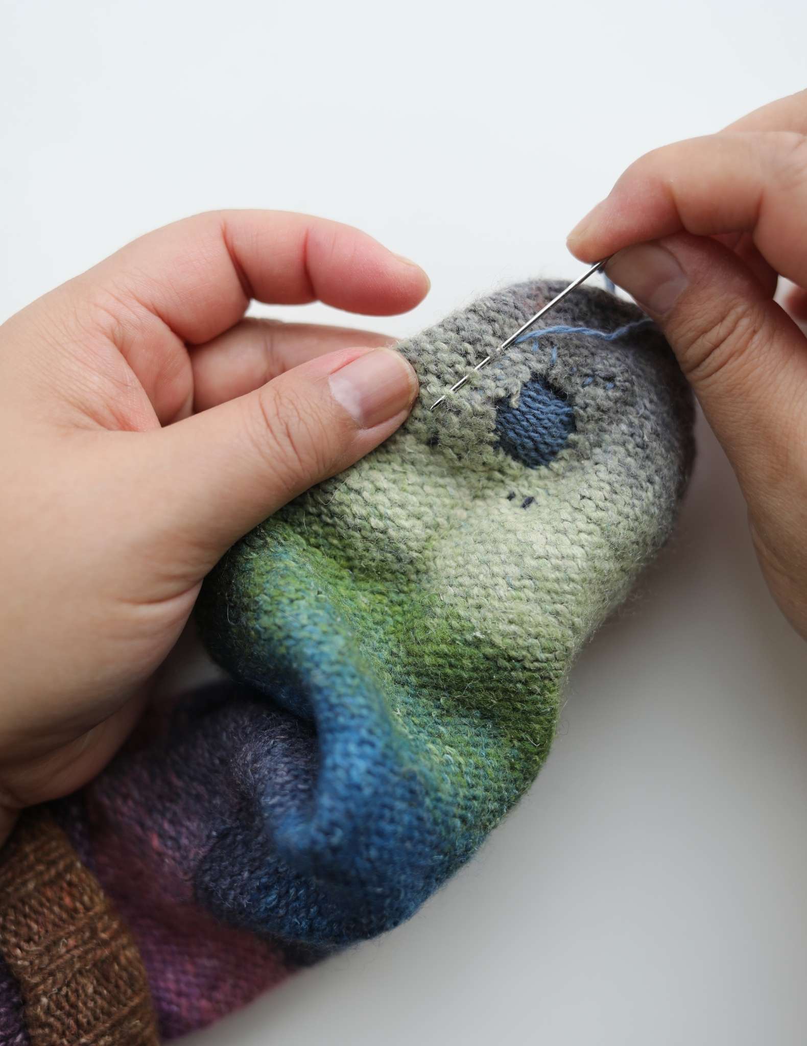 The darned sock is show from the inside, and the loose threads are being tightened and sewn down.